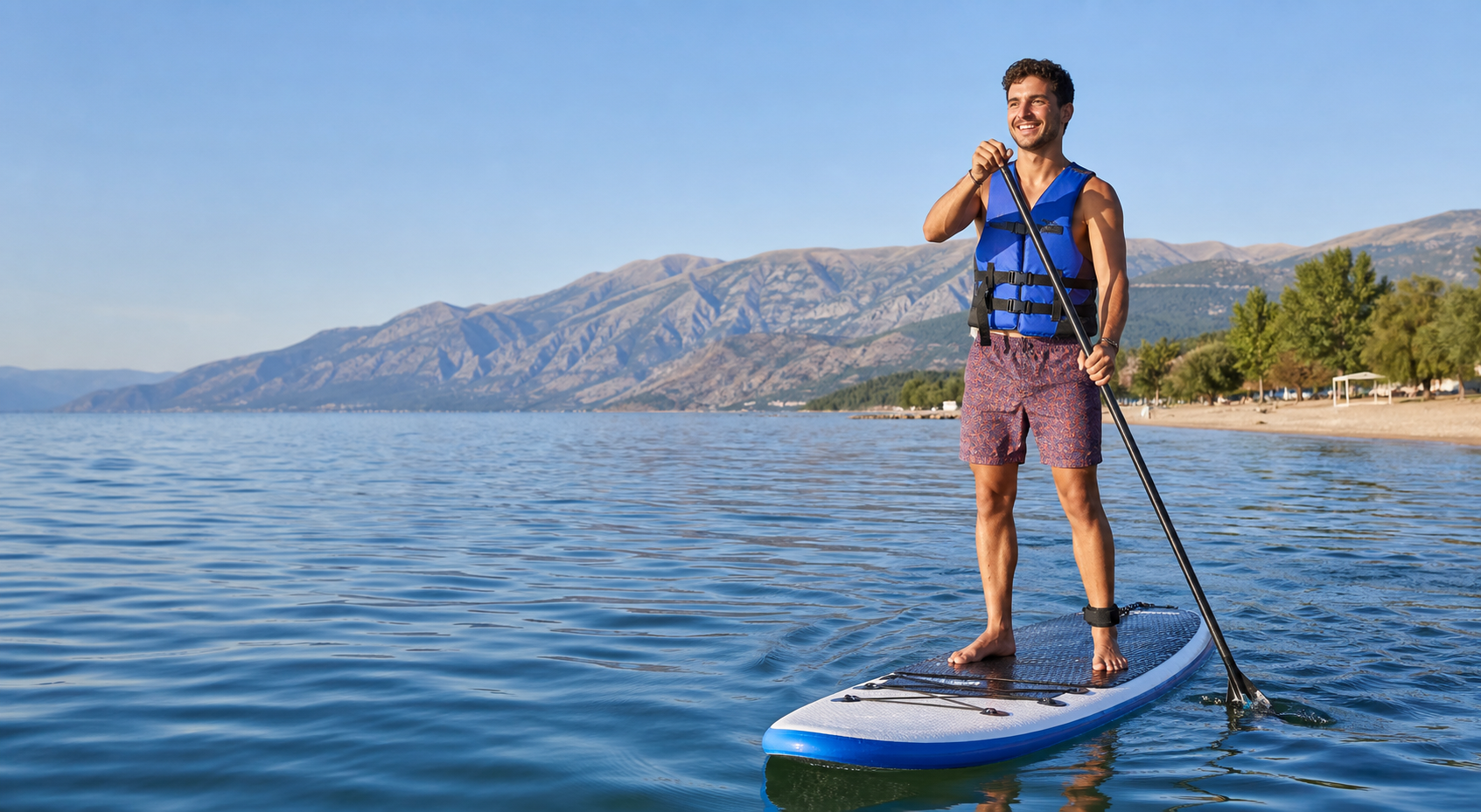 Traveler paddleboarding on Lake Ohrid with mountains behind Pogradec, Albania