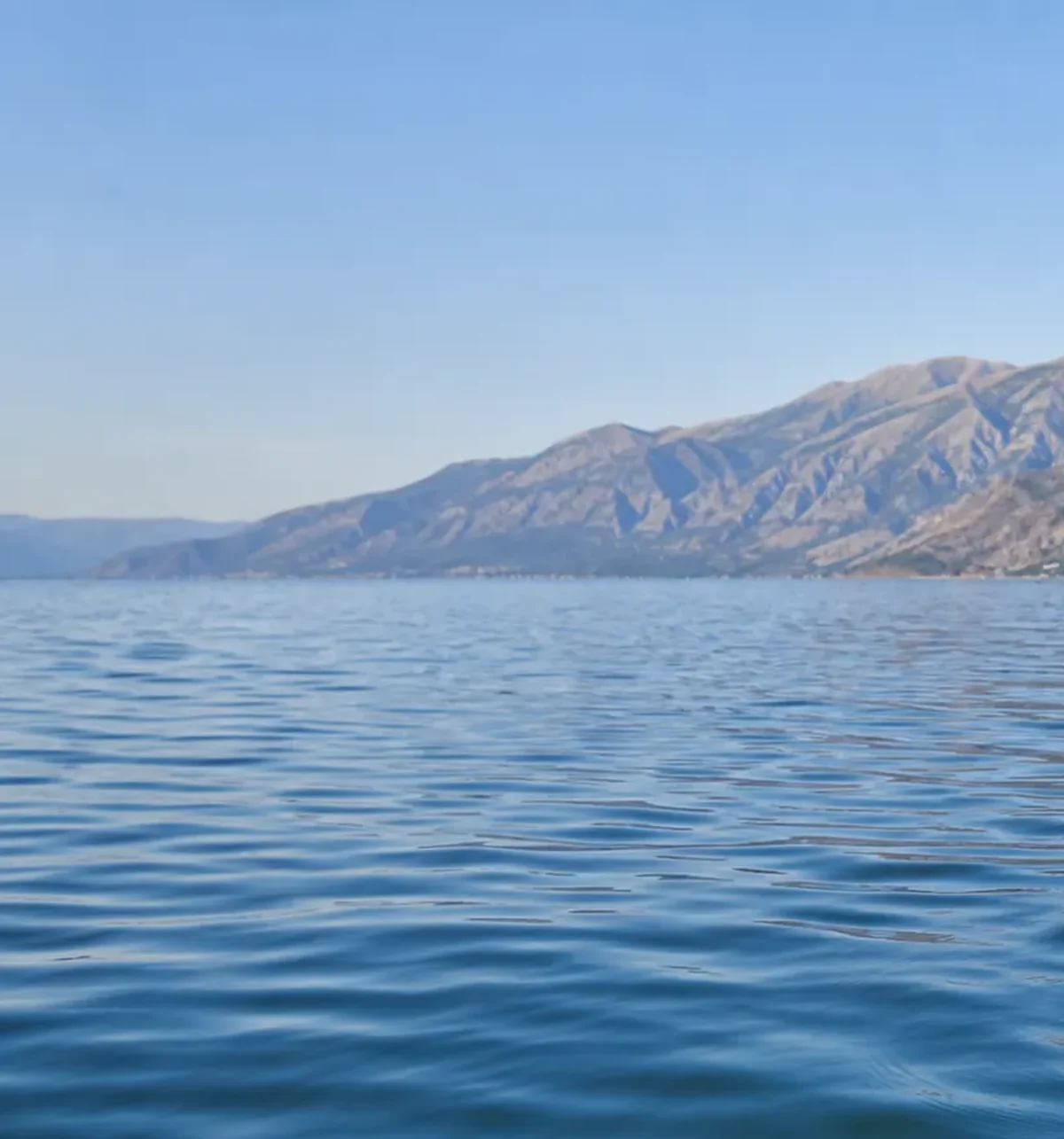 Calm blue water on Lake Ohrid with mountains above Pogradec, Albania